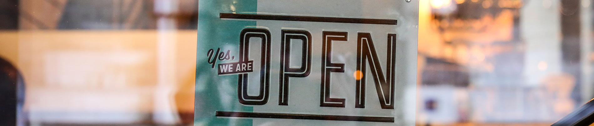 An open sign hanging in a shop window.