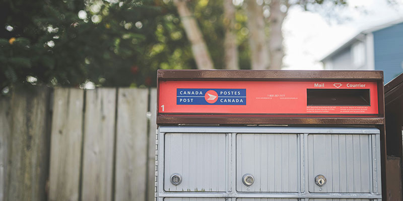 Close up photo of a Canada Post mailbox outside somewhere.