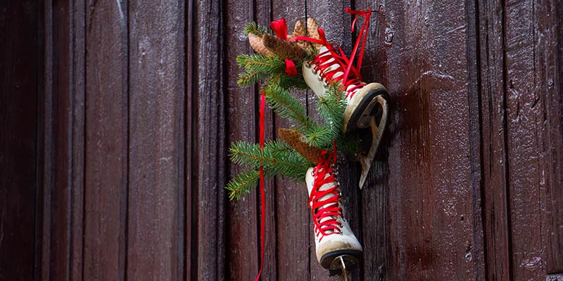 Skates hanging up with christmas decorations stuck in them.