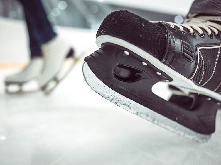 A close up photo of some ice skates on the rink.